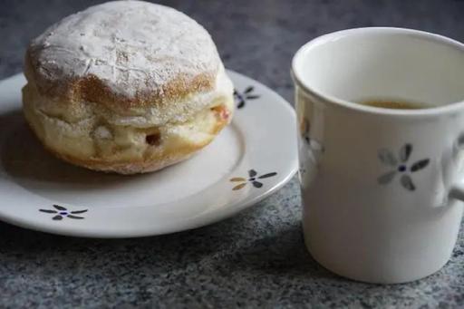 Scone on a plate with a mug of tea