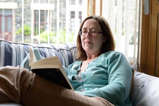 Woman on sofa reading murder mystery